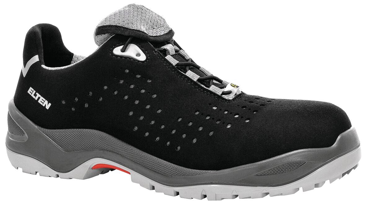 The shoe is black with gray accents. It has a flat sole, lacing, and ventilation holes. The upper is made of a soft, durable material. Ideal for work and leisure.