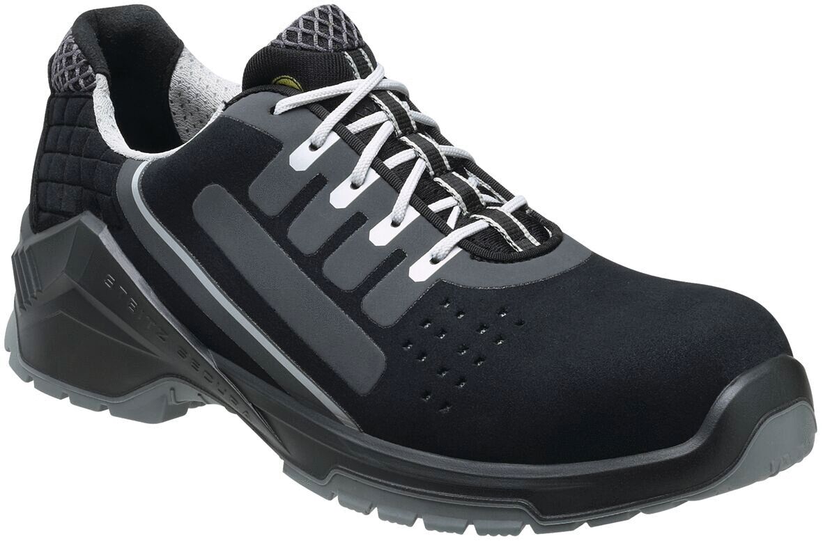 The shoe is a black safety shoe with a sturdy sole. It has a padded tongue and laces. The sides feature reflective elements for visibility and safety.