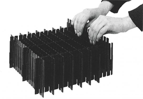 The image shows two hands working on a rectangular object with many vertical bars. The bars are black and arranged orderly. The object has a flat base and a compact shape.