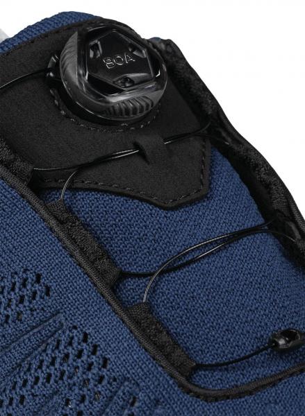 The image shows a dark blue shoe with a special closure system. At the top, there is a three-dimensional element for adjustment to securely fasten the shoe.