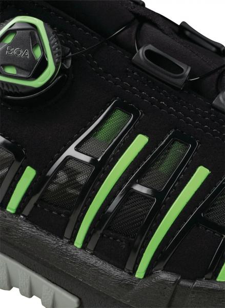 The image shows a black sports shoe with green accents. The surface has transparent inserts and a quick lacing system with a round cord. The sole is grippy.