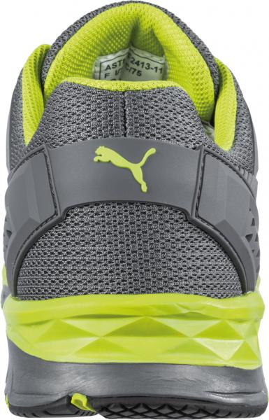 The image shows a gray sports shoe with bright yellow accents. The sole is textured and slightly elevated, the heel has a stabilizing edge. The top features mesh fabric for breathability.