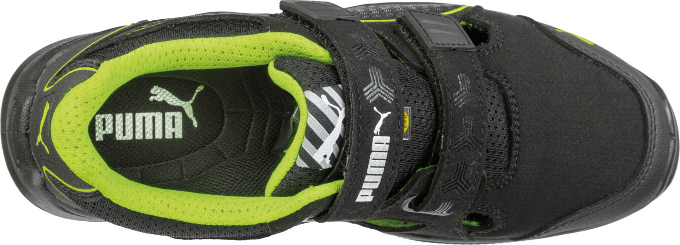 The image shows a black sports shoe with a green insole. The shoe features a wide Velcro strap and a sporty design. The Puma logo is clearly visible.