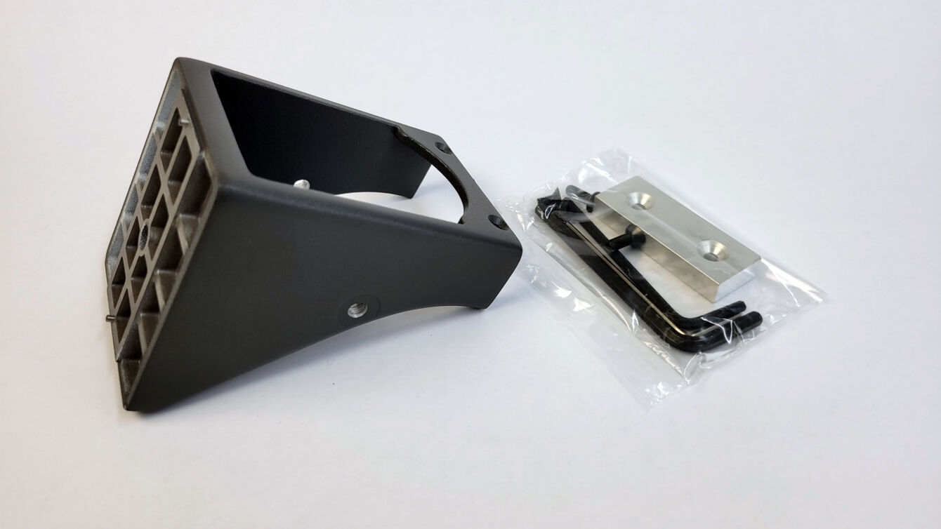 The image shows a black holder with a grippy edge and rectangular openings. Next to it are several small metal parts in a transparent package.