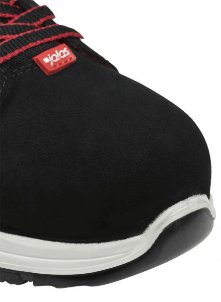 The image shows the front view of a black shoe with a red logo. The shoe has a sturdy construction and a bright, non-slip sole. Laces are visible.