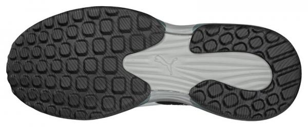 The image displays the sole of a sports shoe. It is predominantly black with a textured surface consisting of many small, round nubs and a smooth area in the center.