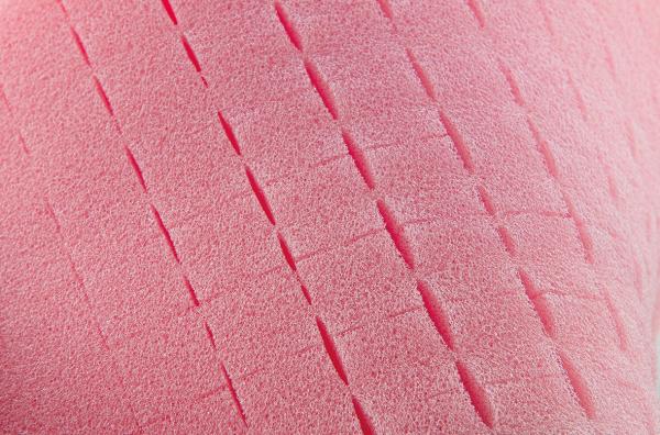 The image shows a structured, pink surface with parallel, slightly notched lines. These lines run in a regular pattern and create a tactile texture.