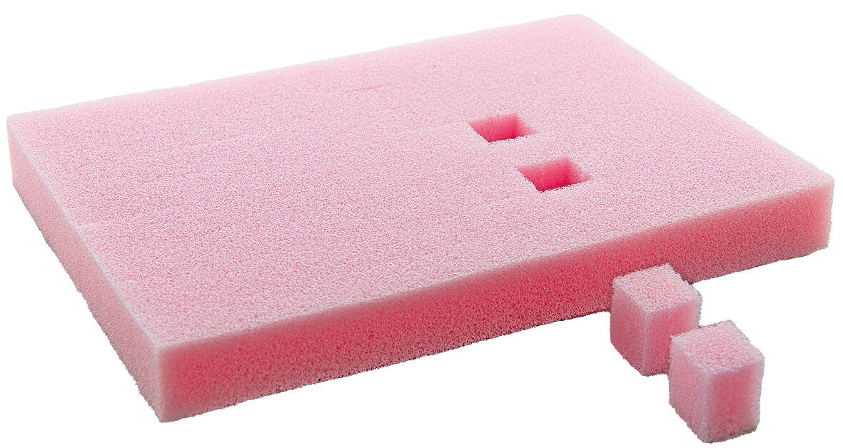 The image shows a rectangular, pink foam block with two smaller, square foam pieces next to it. There are two indentations on the large surface area.