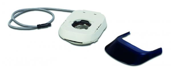 The image shows a technical device with a round, gray cable connection. It features a white, simple casing shape, next to which lies a separate, dark blue cover.