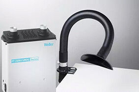 The image displays a smoke extraction device with a silver casing and a flexible, black hose aimed at a work surface.