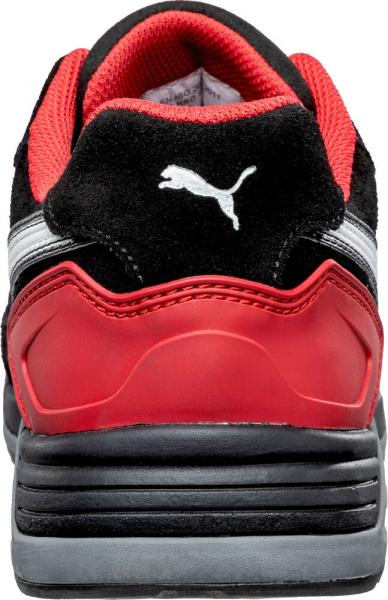 The image shows the rear view of a sporty shoe. It has a black surface, red accents, and a gray sole. A white Puma logo is visible on the heel.