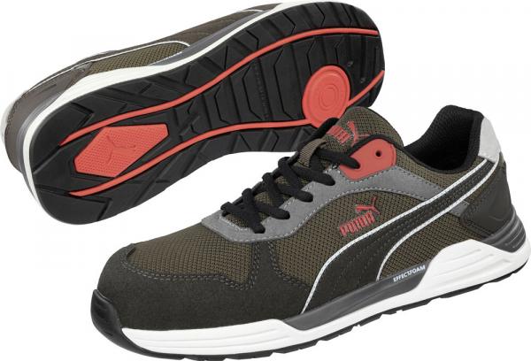 The image shows a pair of athletic shoes in dark green and gray. The shoes have black laces, a white and red sole, and a modern, functional design.