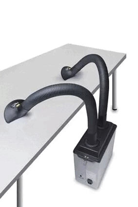 The image shows a device with a rectangular casing, from which two flexible hoses protrude. The hoses are black and slightly curved, running across a table.