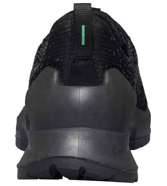 The image shows the rear view of a black sports shoe. The sole is sturdy and has a grippy pattern. There is a green stripe at the top center of the shoe.