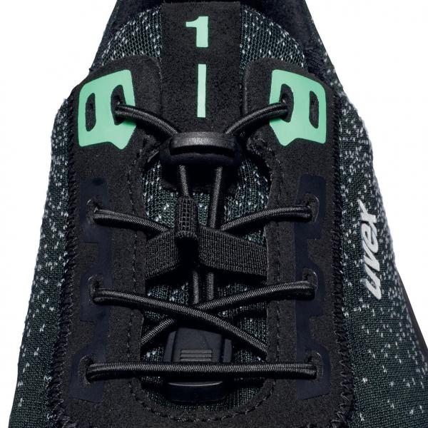 The image shows the lacing of a sports shoe in black with green accents. The shoelaces are tightly braided, and the numbers 1 and 0 are visible on the shoe.