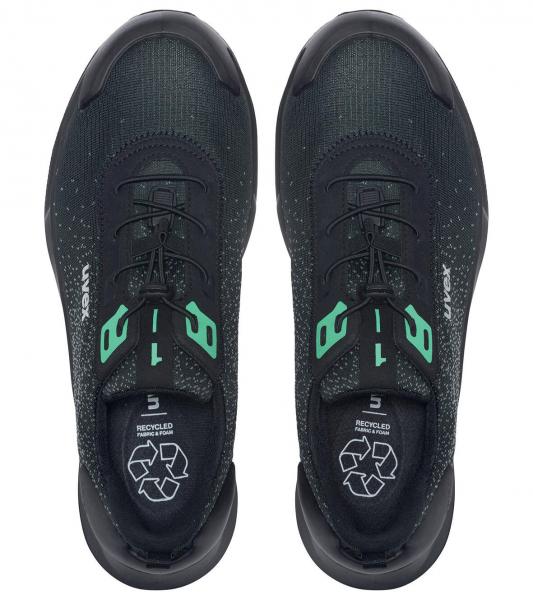 The image shows a pair of black sports shoes with a green accent. They have a modern, simple shape and flat laces. The sole is slightly curved and made from a durable material.