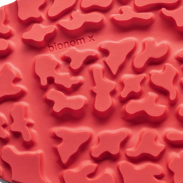 The image shows a red rubber sole with an irregular, textured surface. The patterns are organic and reminiscent of various shapes randomly distributed.