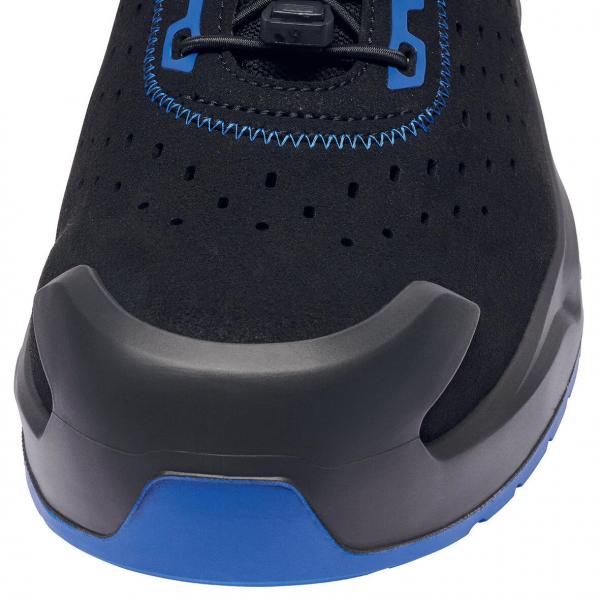 The image shows the front of a black athletic shoe. The shoe has blue accents and a rubber-like reinforcement at the tip. There are small holes for ventilation.