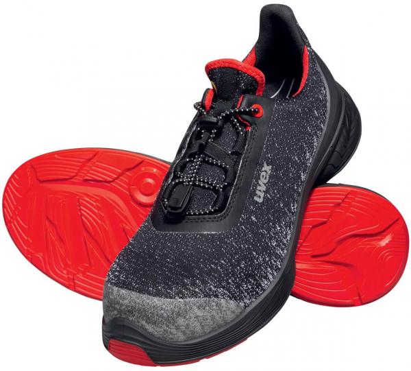 The image shows sports or running shoes. They are primarily black with red accents. The sole is red and non-slip. The shoe features elastic lacing and a padded tongue.