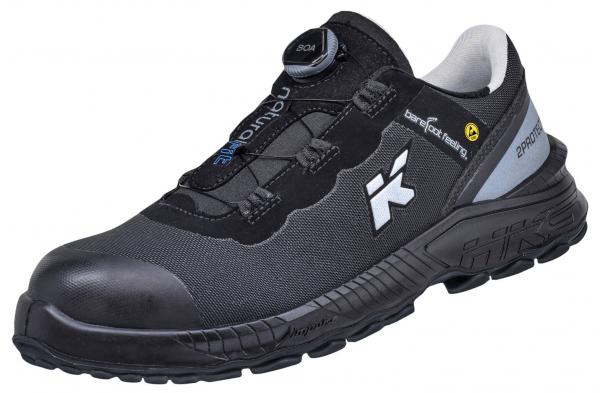 The shoe is black with gray and blue accents. It has a reinforced toe for protection, a quick lacing system, and a non-slip, cushioned sole, ideal for work or leisure.