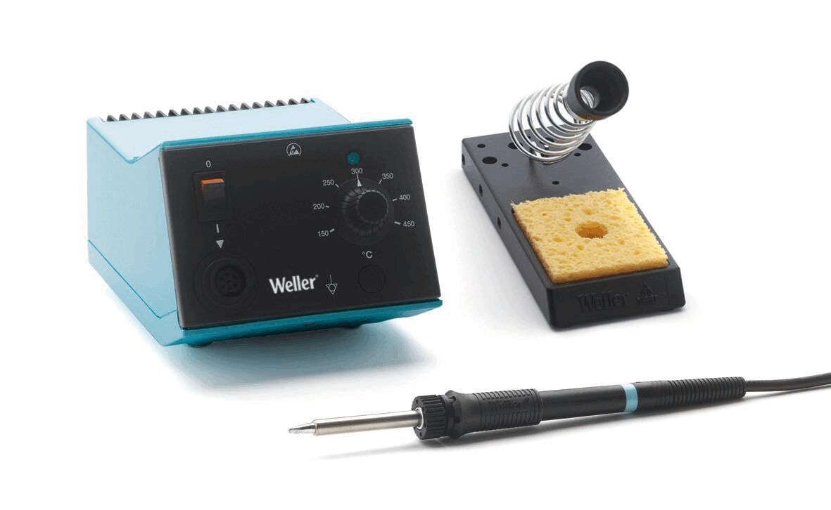 The image shows a soldering station: a blue heat switch with a rotary knob, a solder stand with a sponge, and a soldering tool with a black handle.