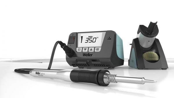 The image shows a soldering iron with digital temperature control. Next to it is a soldering station with a display and a holder for the soldering iron. Everything has a modern, sleek design.