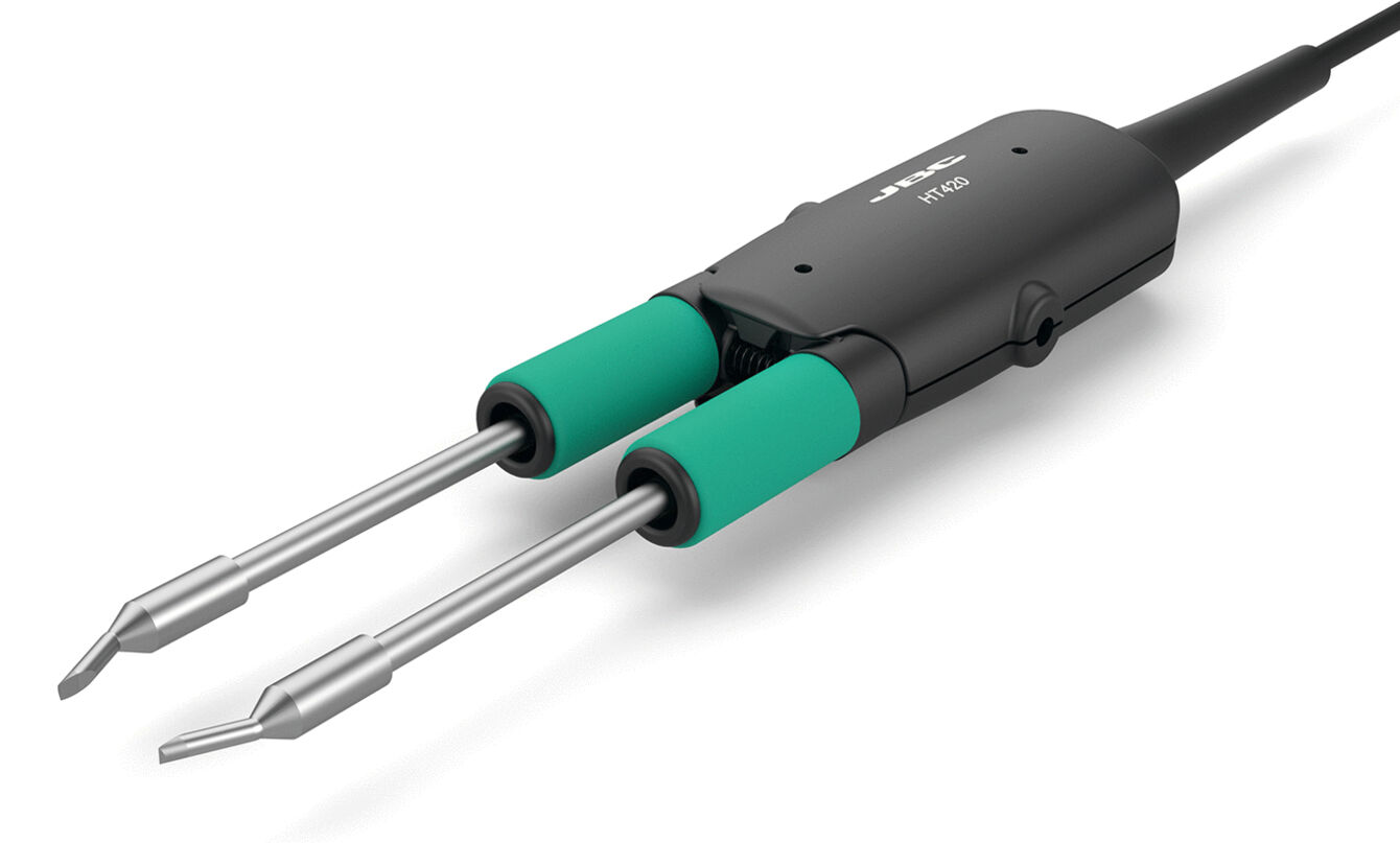 The image shows a soldering iron with two metallic tips and green rubber grips. The handle is black and has a connecting cable. It is used for soldering.