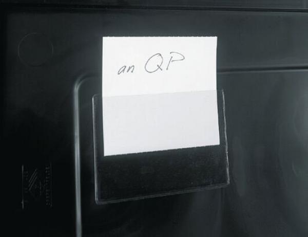 On a black background, a white sheet of paper is stuck. On it, handwritten is "to QP". The sheet has no further decorations or images.