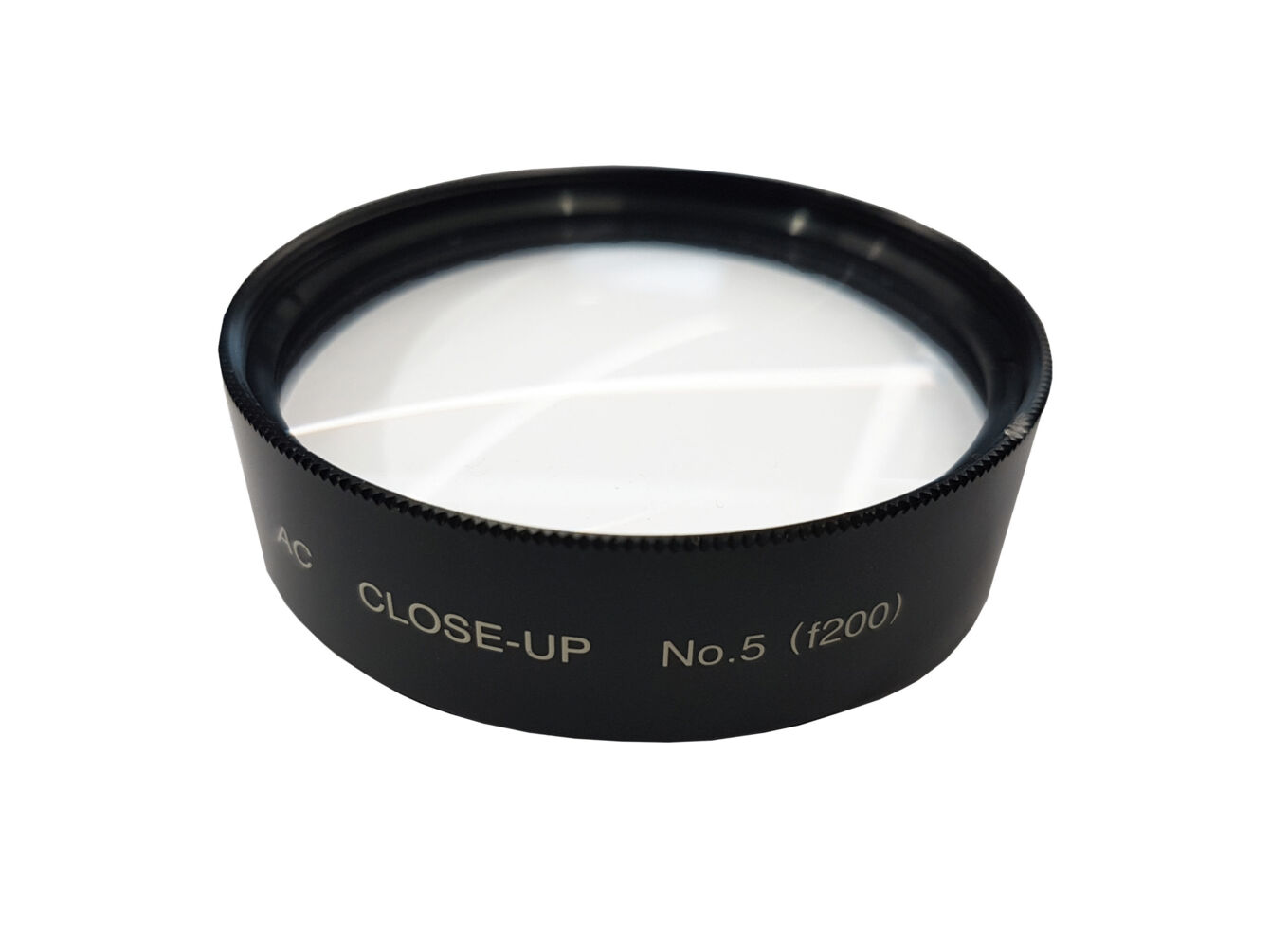 The image shows a round macro filter made of black metal with a smooth, transparent glass surface. On the filter, it reads "CLOSE-UP No.5" and a serial number. The filter is used for close-up photography.