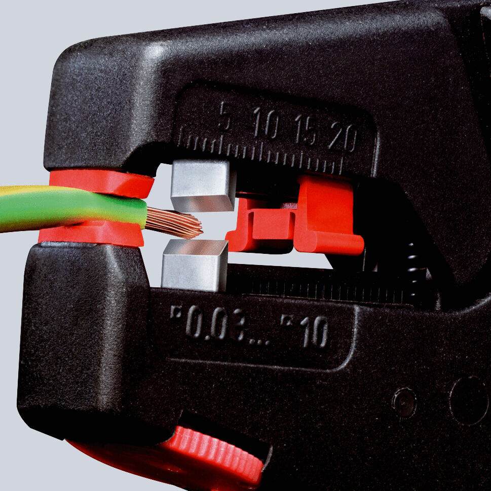 The image shows a wire cutter gripping a green and a brown wire. The cutter has a black and red color scheme and displays the cutting surfaces for the wire.