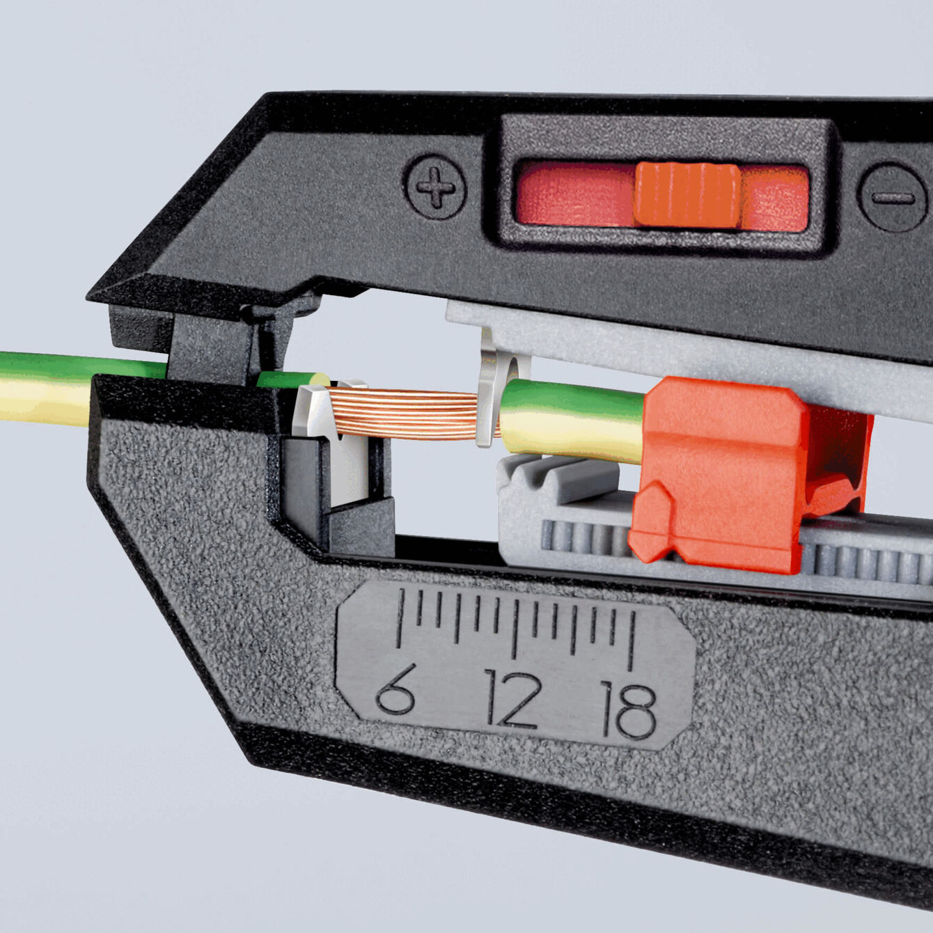 The image shows an electric cable cutter. A green-yellow cable with copper wires is visible in the holder. Scale from 6 to 18 is visible on the device.