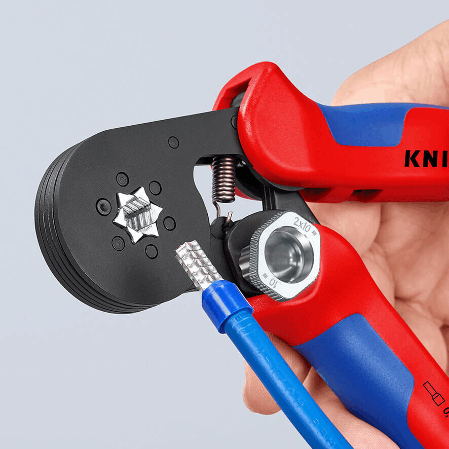 The image shows a hand holding a red and blue crimping tool. The tool has a black surface and an opening into which a blue wire is being inserted.