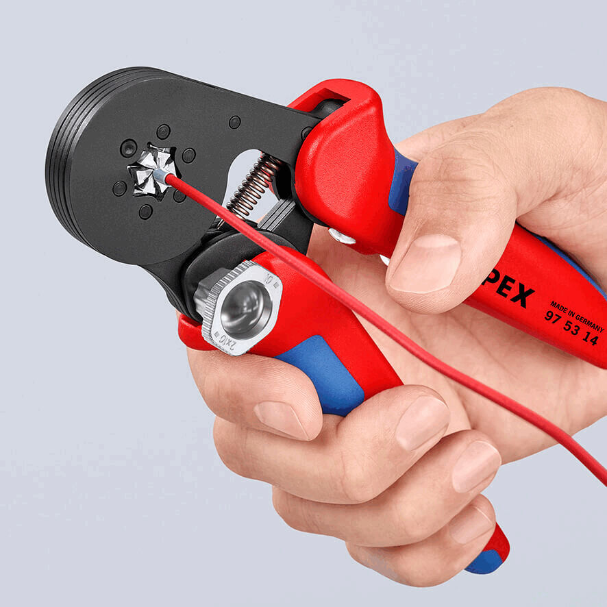 The image shows a hand holding a red and blue pair of pliers. The pliers are used for stripping wires, with a red cable currently being clamped.