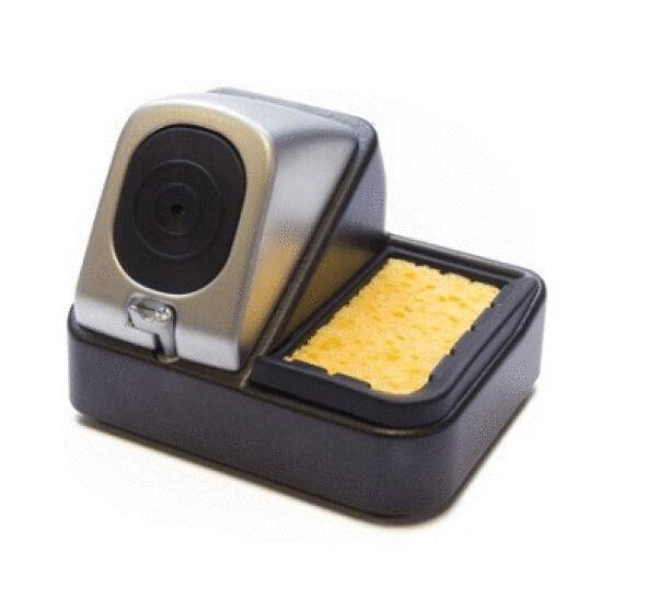 The image shows a stylish, rectangular pen holder in black with a silver top. In the center, there is a yellow sponge, ideal for cleaning writing utensils.