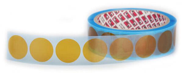 The image shows a roll of stickers. The stickers are yellow and round, arranged on a transparent film that is wrapped around the roll.