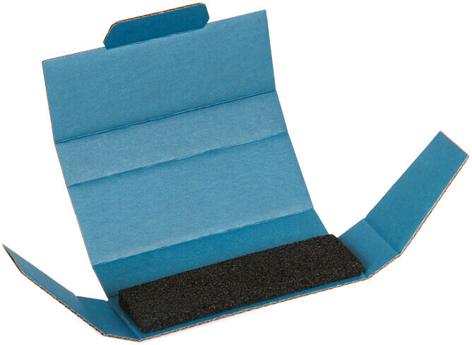 The image shows an opened blue package containing a black sponge-like inlay. The side flaps are unfolded, with the top flap slightly raised.