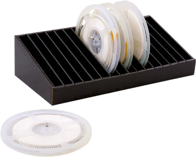 The image shows a black storage box with compartments for several transparent film reels. One reel is lying next to it. The reels are circular with a central opening.