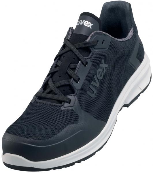 The shoe is a sports or casual shoe in black with gray accents. It features a breathable upper, a padded tongue, and a flexible, white outsole.