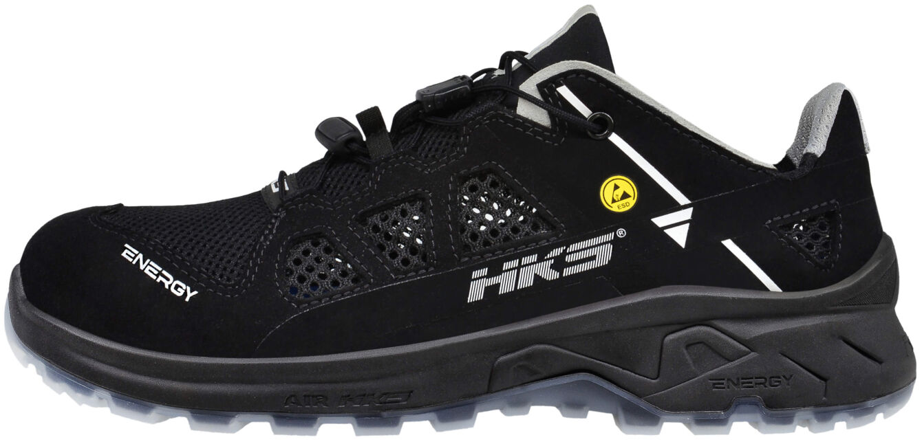 The image shows a black sports shoe with breathable mesh material and reflective elements. It has a sturdy sole and modern lacing. A yellow logo is visible.