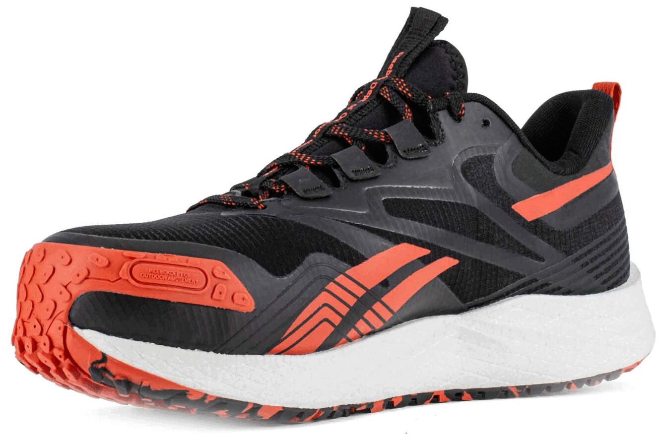 The shoe is sporty and lightweight, primarily black with orange accents. The sole is well-profiled, the upper part features breathable materials and a padded tongue.