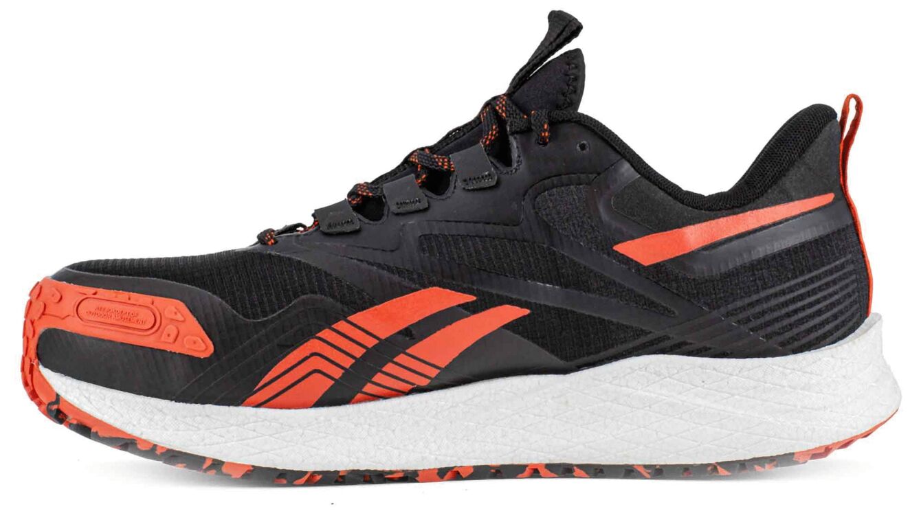 The shoe is sporty and black with orange accents. It has a flat, thick sole and offers good cushioning. The laces are black, and the surface has a modern look.