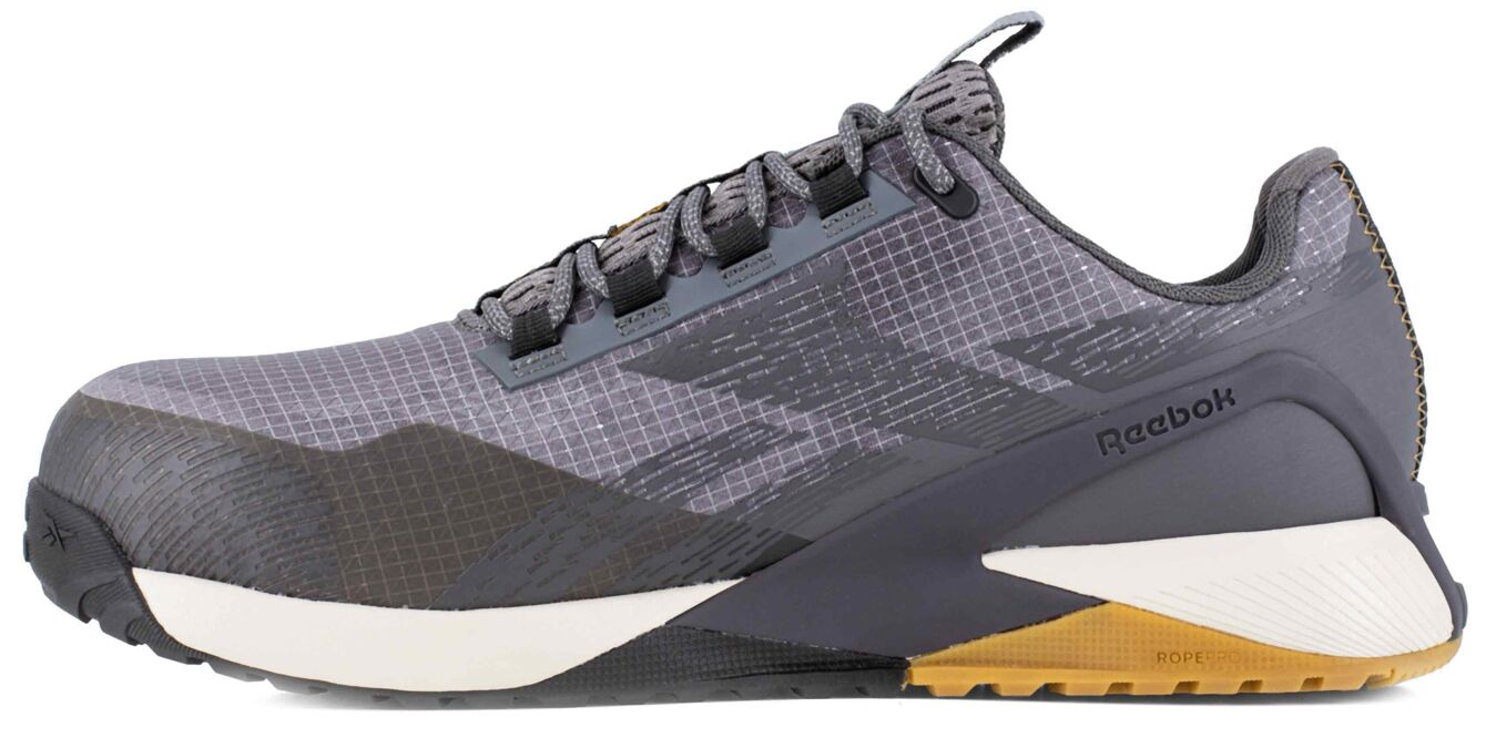 The shoe is sporty and modern, made of gray material with a textured surface. The sole is stable, the toe rounded, and the laces are black. A logo is visible.