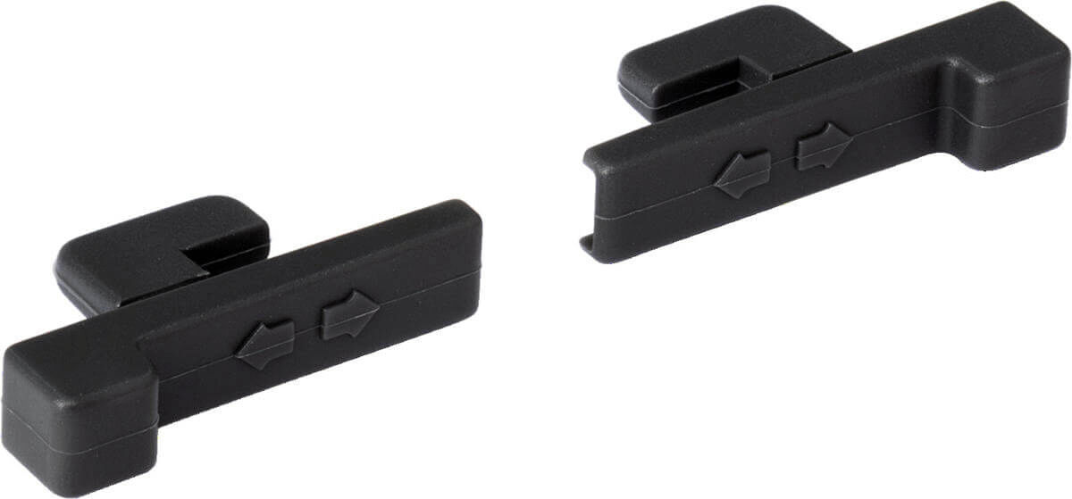 The image shows two black clip-like parts. Each has a rectangular shape with small arrow symbols indicating the direction. They are made of matte plastic.