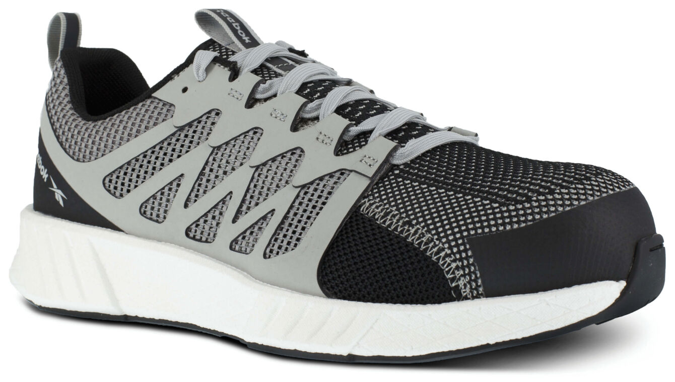 The shoe is a sporty training shoe in black and gray. It has a mesh upper with snake patterns, flat laces, and a thick, white sole for good cushioning.