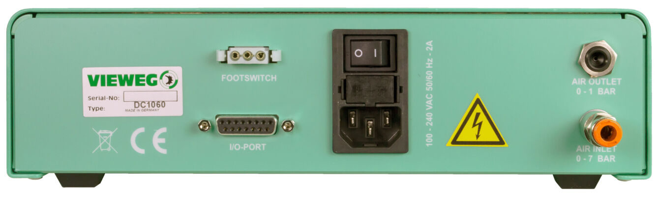 Das Bild zeigt die Rückseite eines grünen Geräts mit mehreren Anschlüssen: einen Netzschalter, Buchsen für Fußschalter und VG-Port, sowie Ausgänge für Luft mit Druckangaben (0,1 und 0,7 bar).