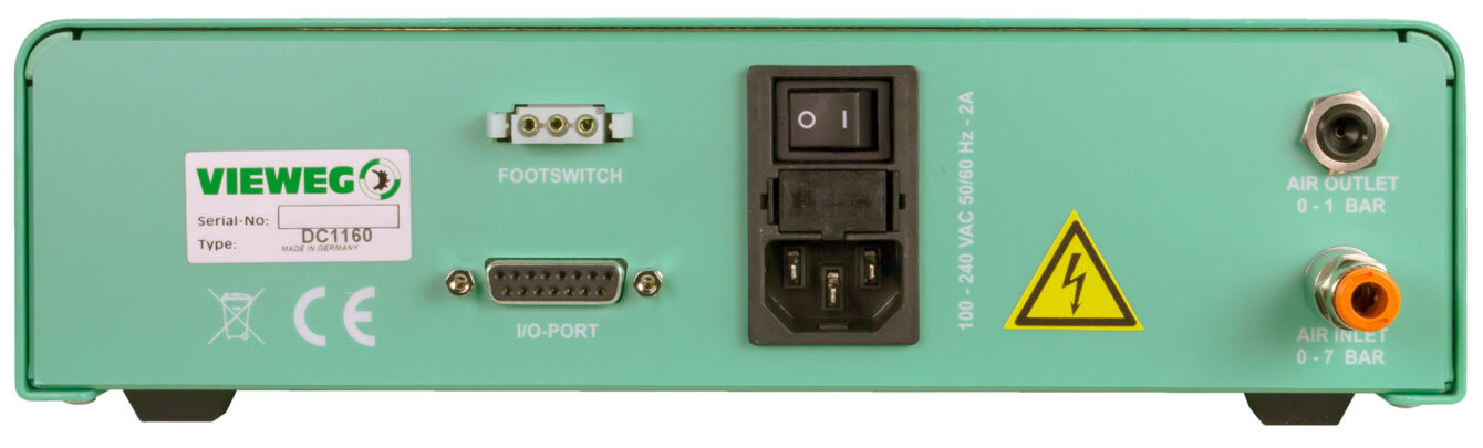 The image displays the back of a green device with connections: a foot switch, an IO port, a switch, and air connectors. There are warning symbols and technical information.