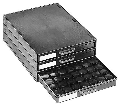 The image shows a three-part black drawer box with an open compartment. In the drawer, there are many round, flat objects that look like lids or plates.