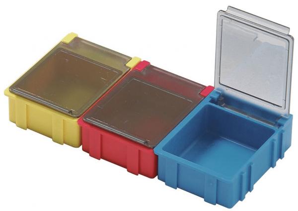 The image displays three small storage containers in sequence: yellow, red, and blue. The blue container has a transparent lid, while the other two are closed.